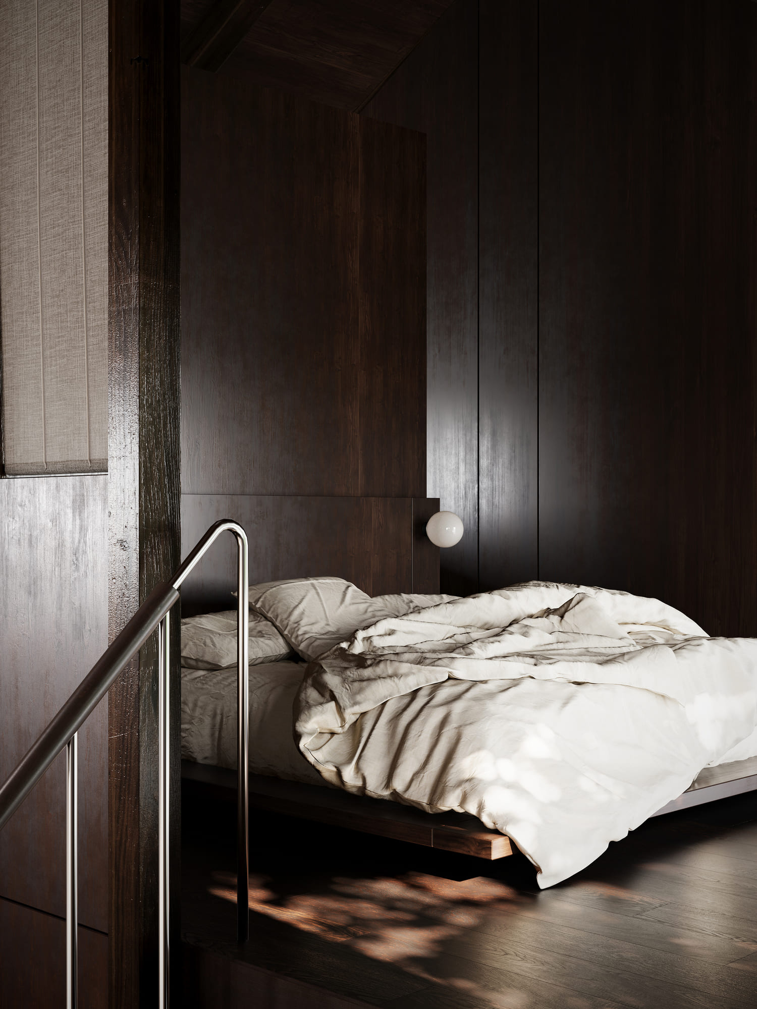 Unmade bed with rumpled white sheets and pillows in a dark wooden room with a metal handrail in the foreground and soft natural light creating shadows on the wooden floor.