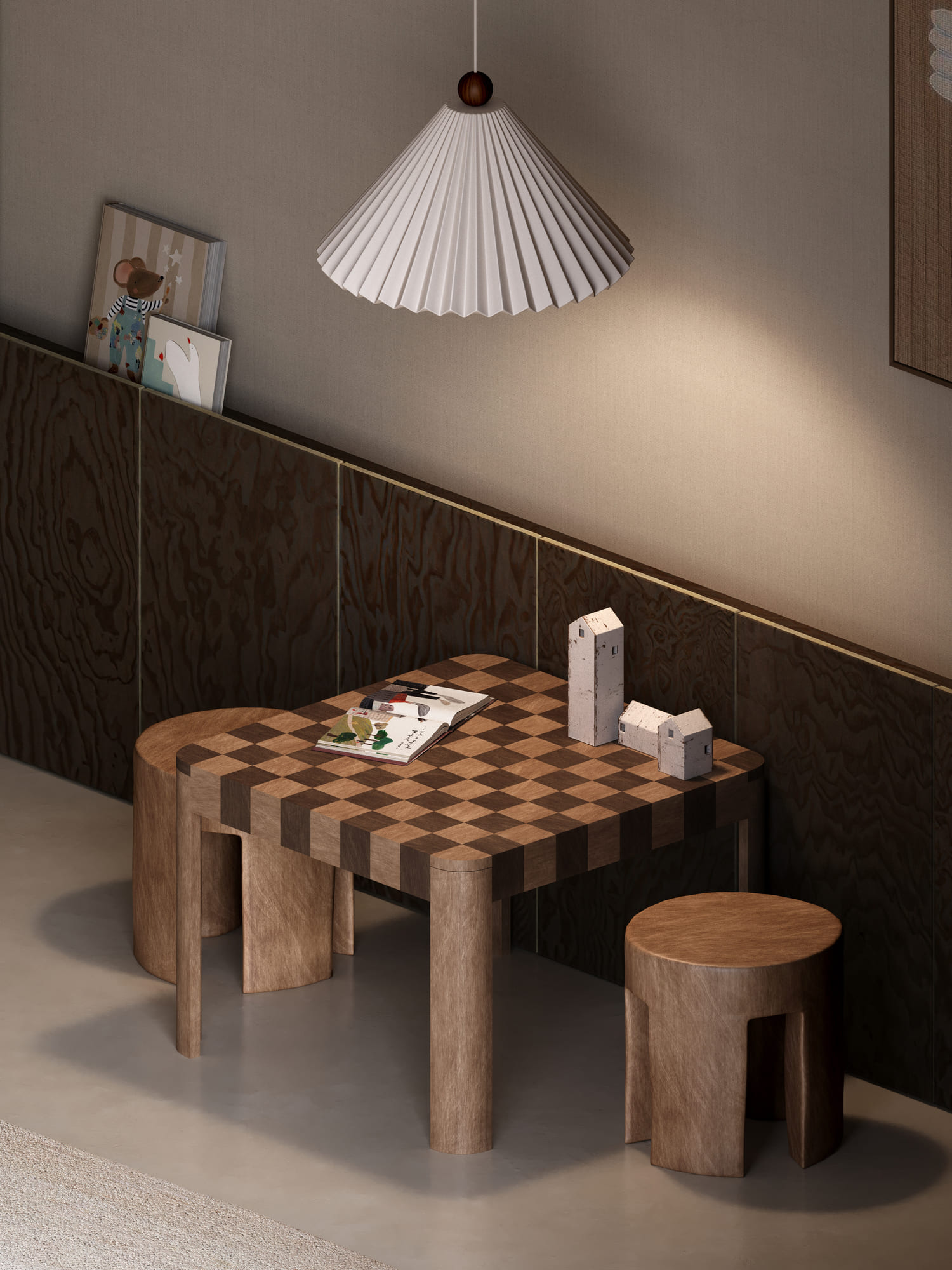 Modern interior scene with a wooden checkered table and matching stools, a white pleated pendant lamp hanging above, children's books leaning against a dark wooden panel wall, and two small white decorative house models on the table.