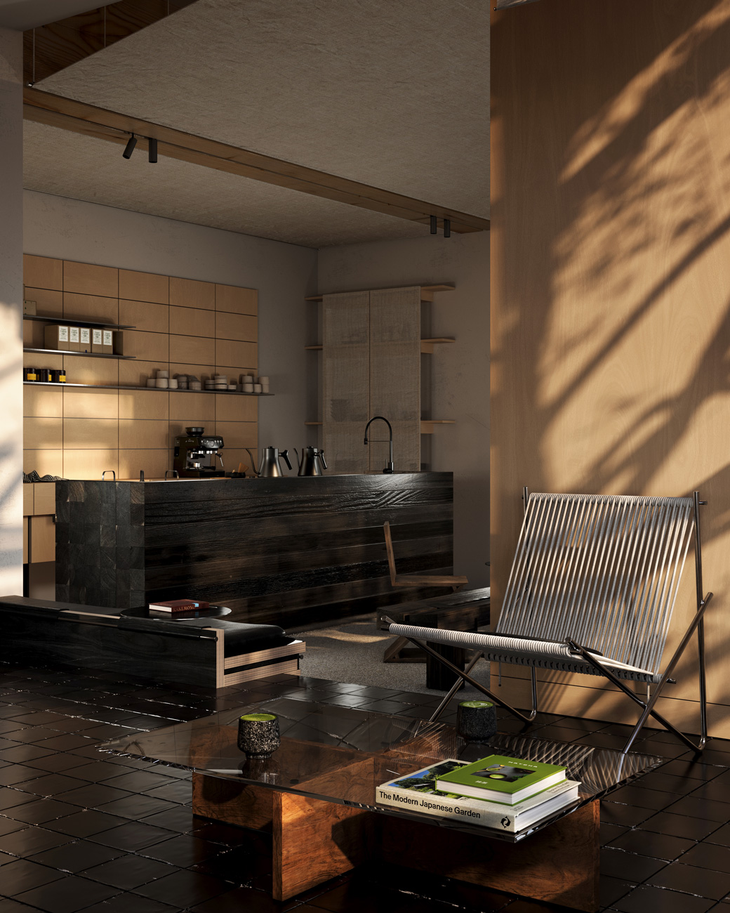 Modern minimalist living space featuring a dark wood kitchen island with metal kettles and a coffee machine in the background, a glass coffee table with wooden base holding books including 'The Modern Japanese Garden', and a metal-framed chair with woven white straps. Warm natural light casts shadows on a large wooden wall and black tiled floor.