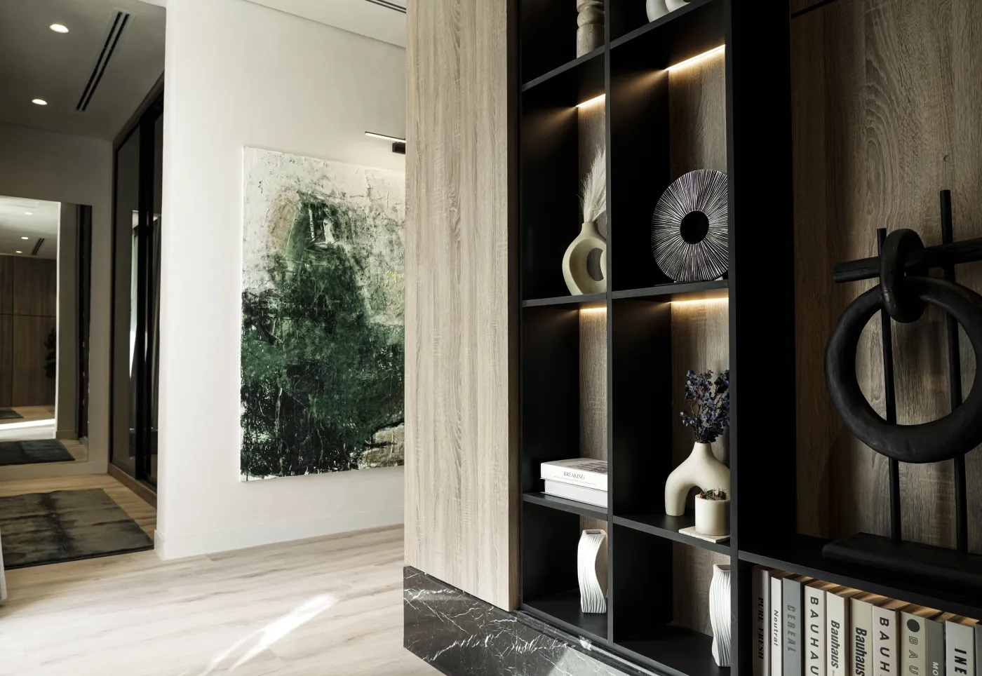 Modern room with black shelving unit displaying books and decorative vases, and abstract wall art.