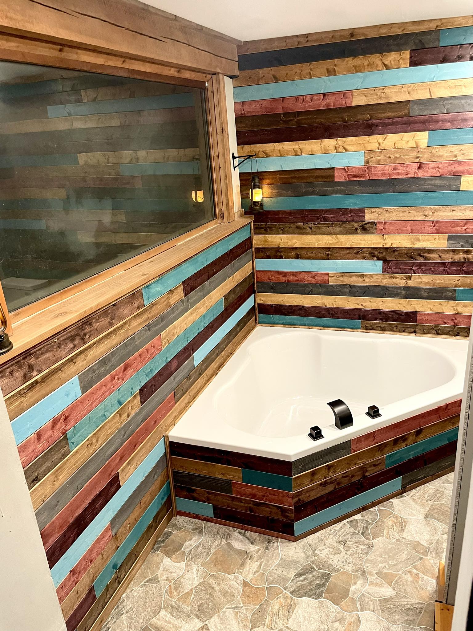 Bathroom corner with white tub and multicolored wooden panel walls and a tiled floor.