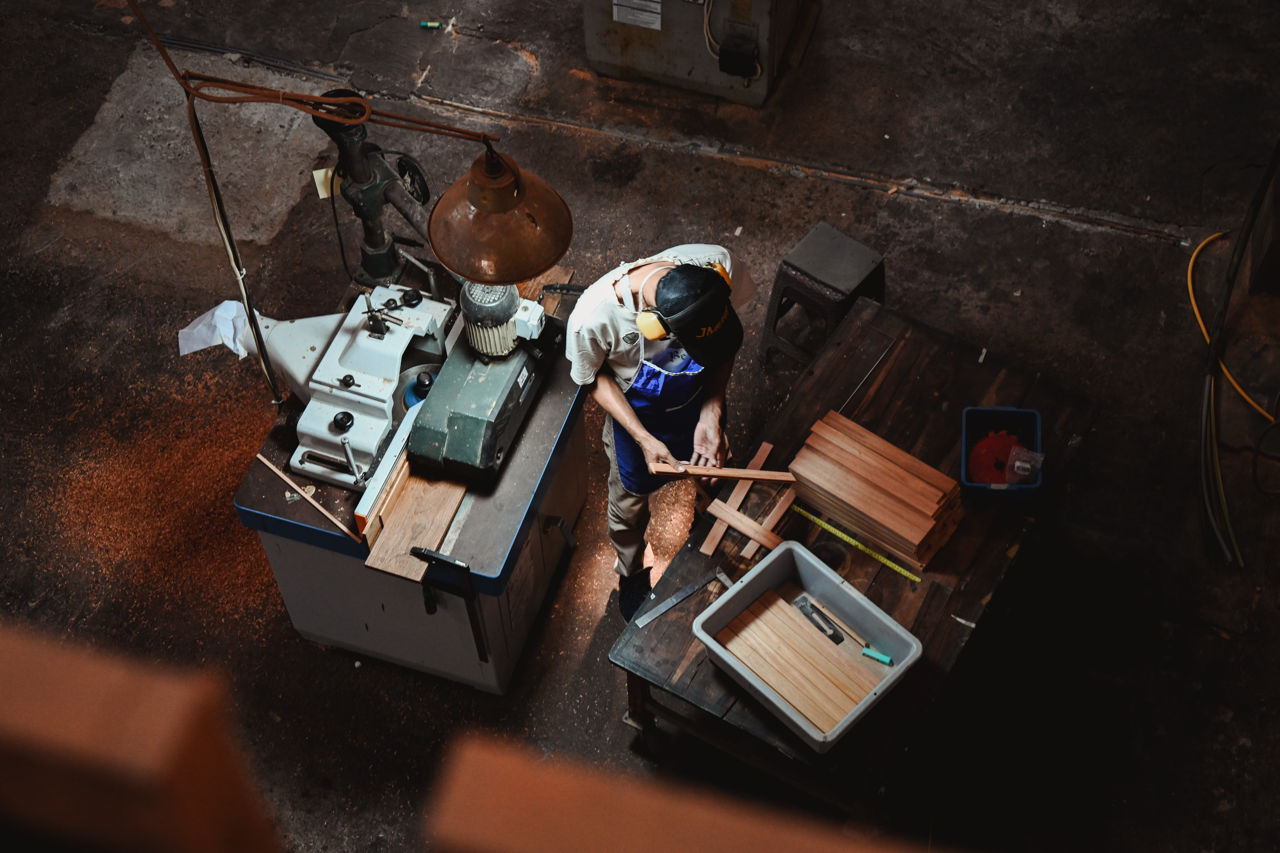 Craftsman shaping wood in the workshop, overhead view.