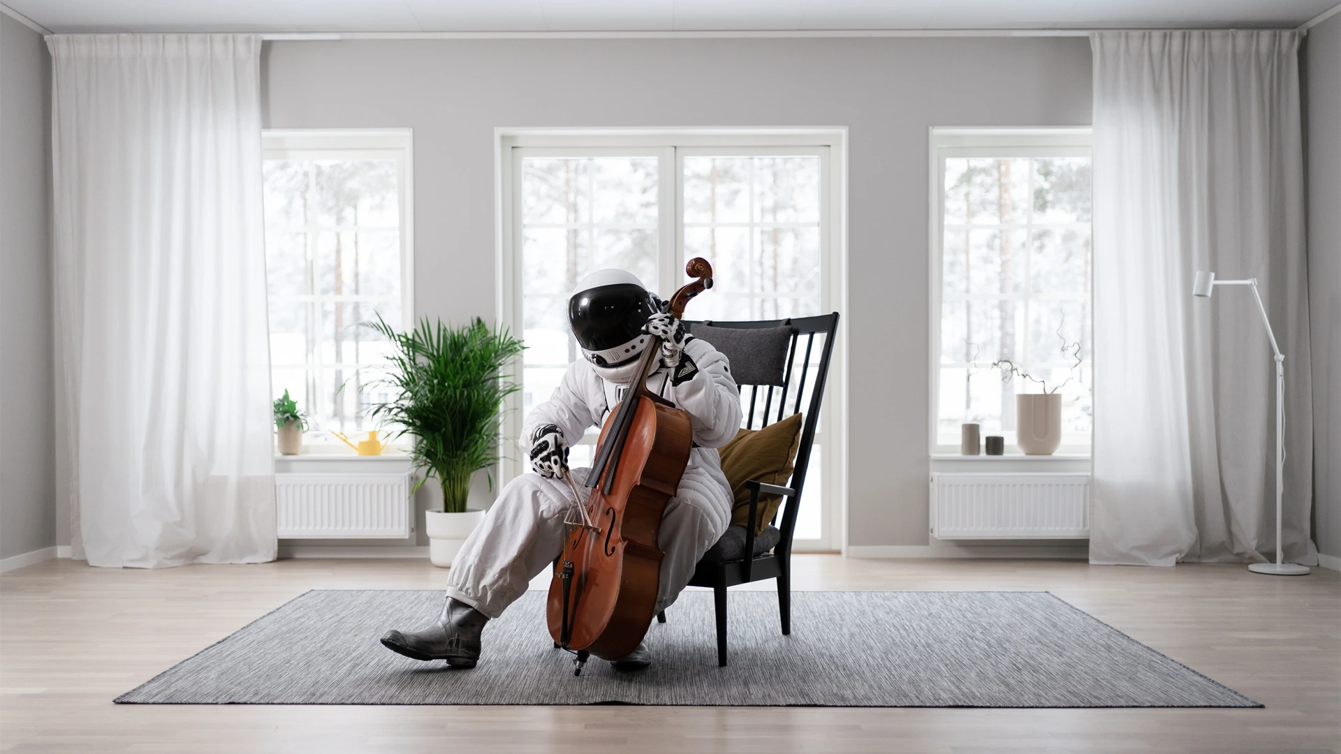 Astronaut spelar cello i ett ljust vardagsrum.