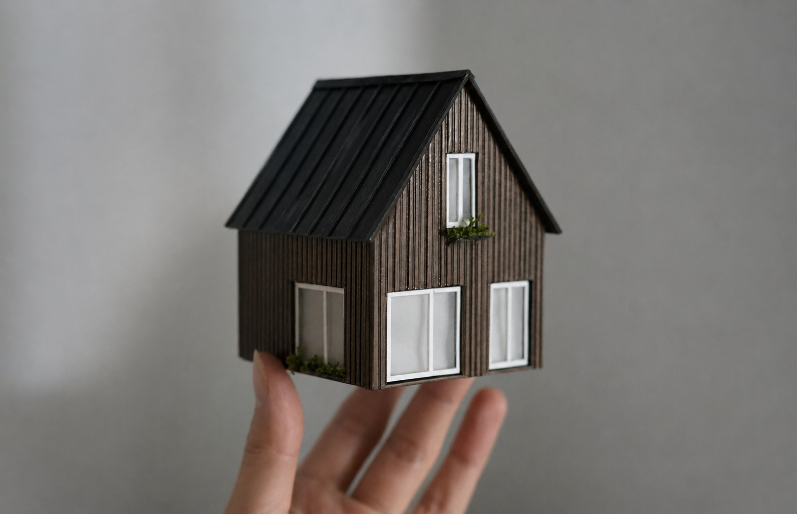 En hand håller en modell av ett hus.