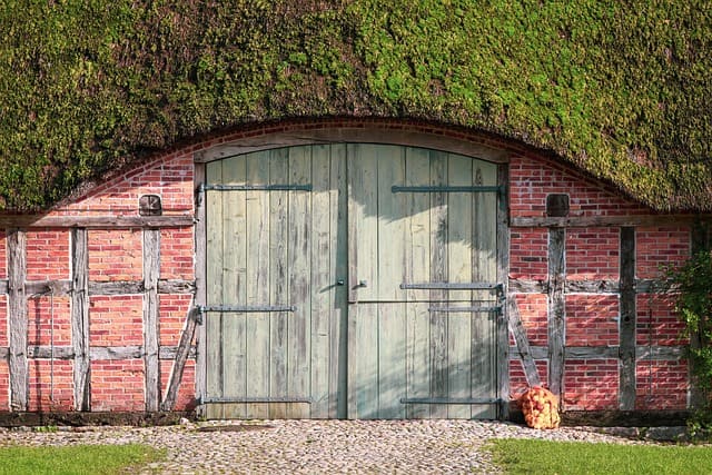 Historisches Fachwerkgebäude mit Reetdach und großer Holztür im ländlichen Stil