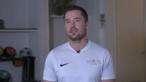 Trainer in wit Nike-shirt staat in een sportruimte met uitrusting