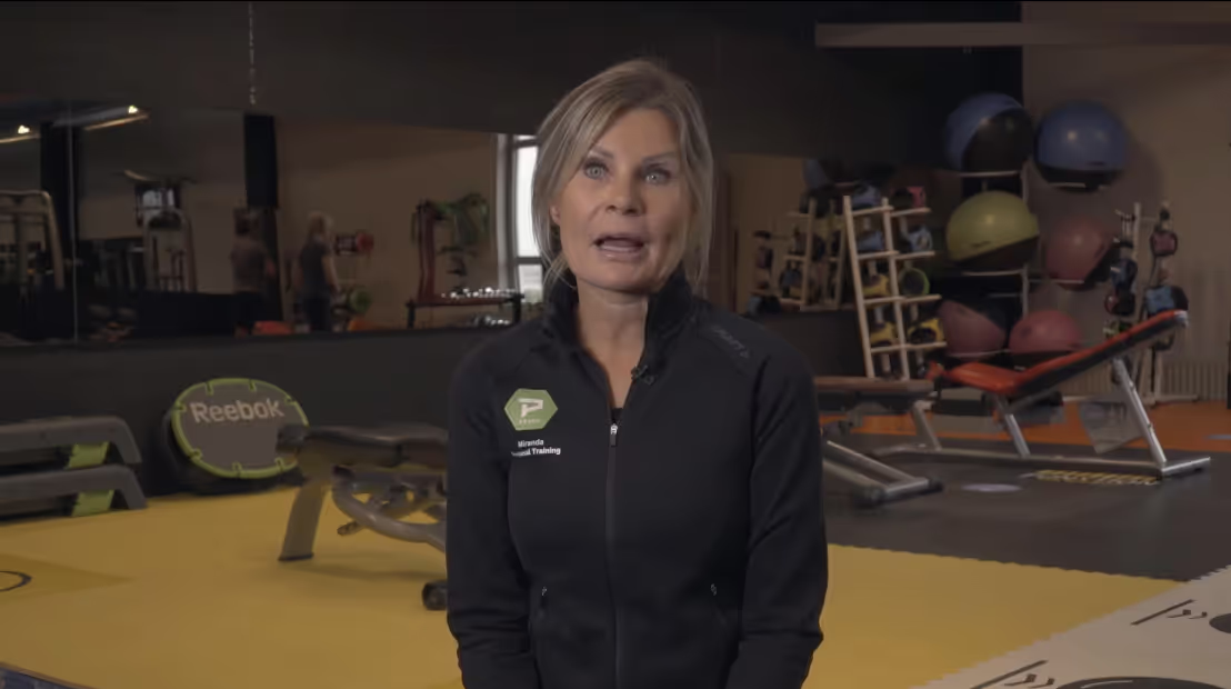 Vrouw in zwarte Reebok-jas in sportschool met fitnessmaterialen