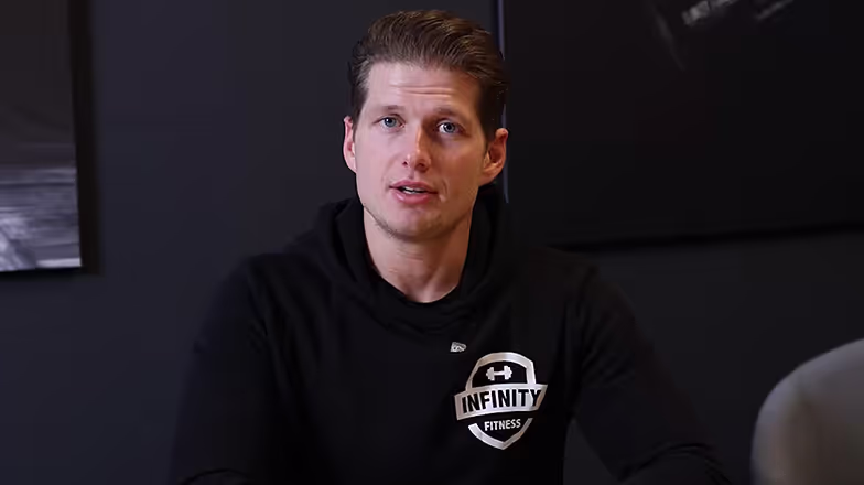 Fitness-instructeur in zwart shirt met Infinity Fitness-logo
