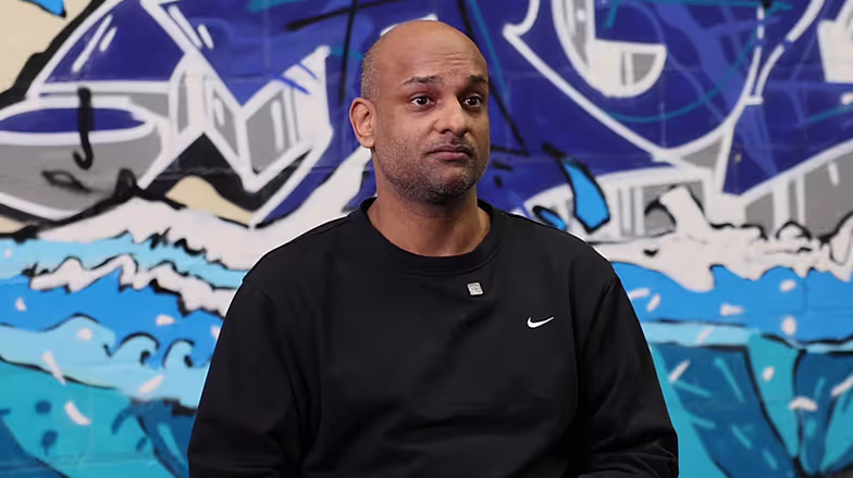 Man in zwart Nike-shirt voor blauwe en grijze graffiti-achtergrond