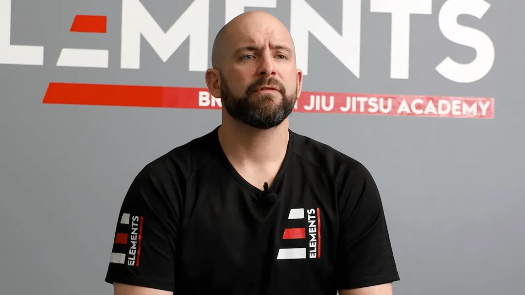 Kale man in zwart shirt voor Elements Jiu Jitsu Academy achtergrond