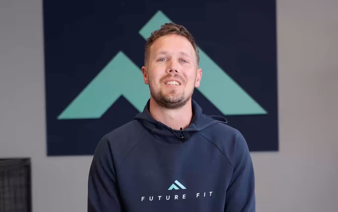Glimlachende man in Future Fit hoodie voor blauwe en groene achtergrond