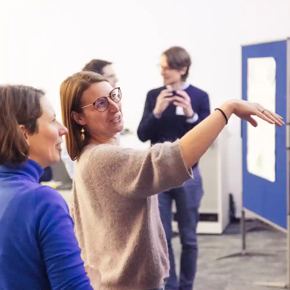 Workshop in Berlin: Links steht Bärbel Becker und rechts eine Teilnehmerin und erklärt etwas vor einer Pinnwand-Situation