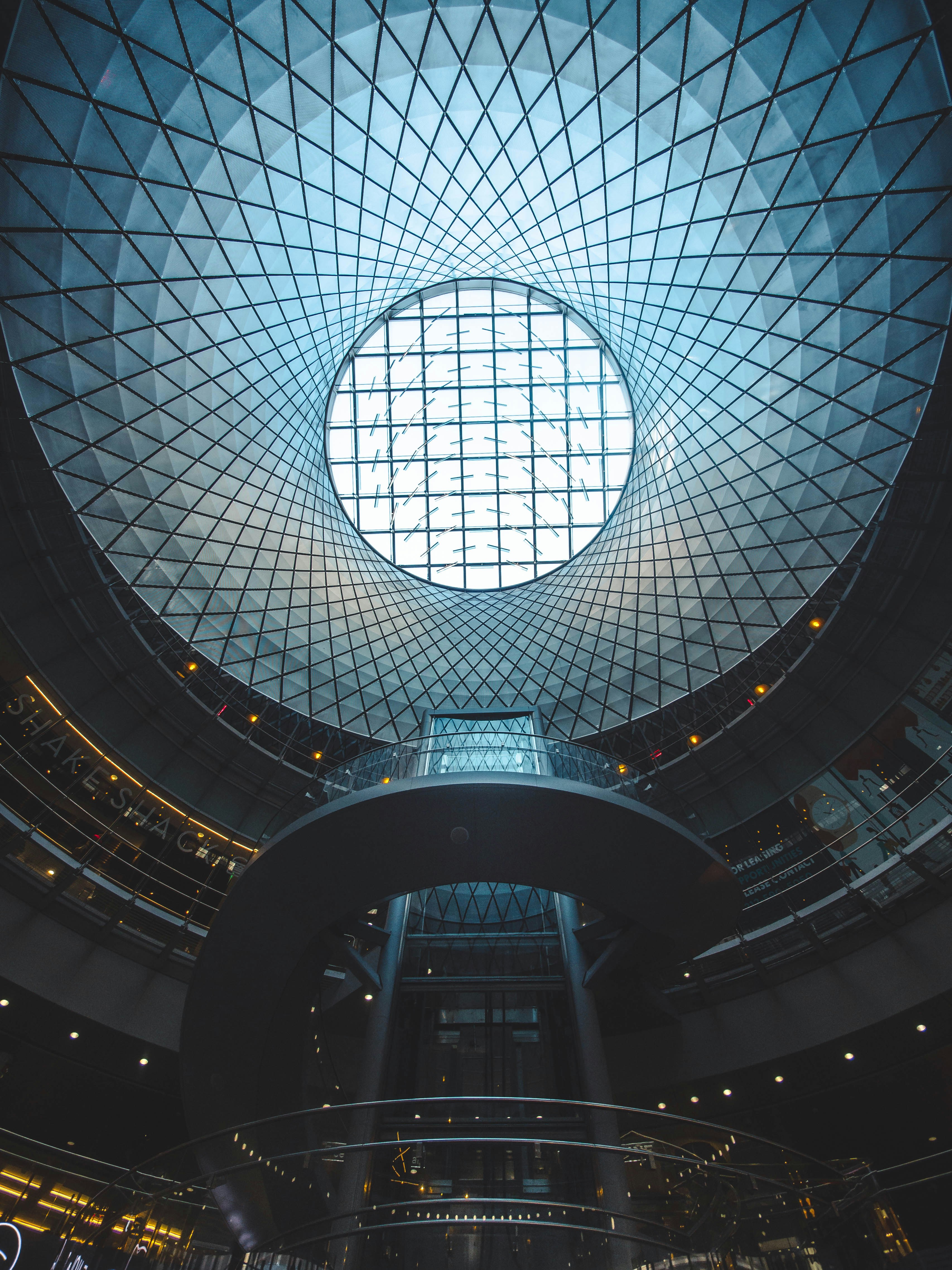Interior view of a circular glass ceiling with a spiral walkway inside a modern building.