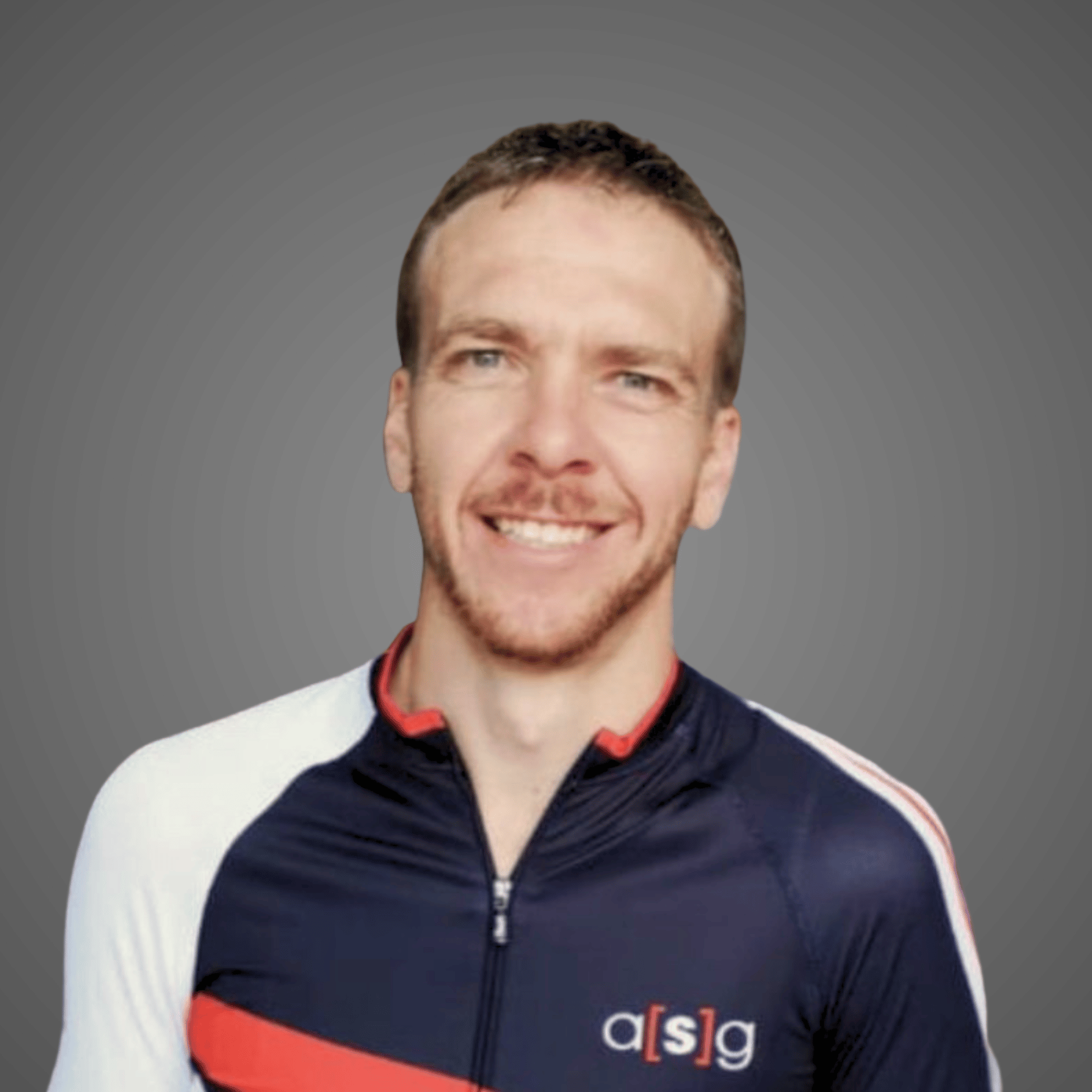 Smiling man with short brown hair wearing a navy, white, and red athletic jacket with logo a[s]g.