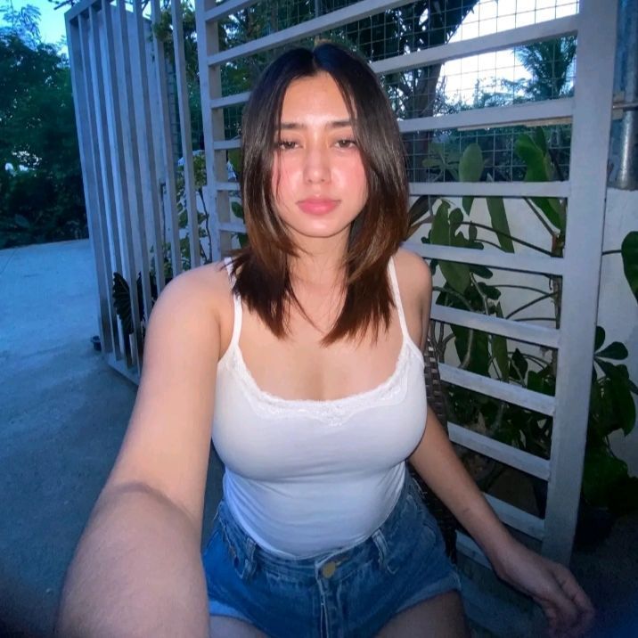 Beautiful female companion in Ghaziabad Escorts wearing a white tank top and denim shorts.
