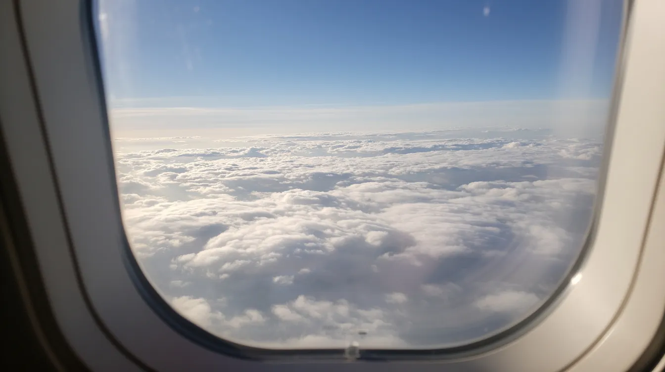The image depicts a serene view from an airplane window, showcasing a calm blue sky above a soft layer of white clouds, perfect for those tracking flights or planning their next journey. This tranquil scene highlights the beauty of flight and the vastness of the skies, ideal for both student pilots and experienced aviators alike.