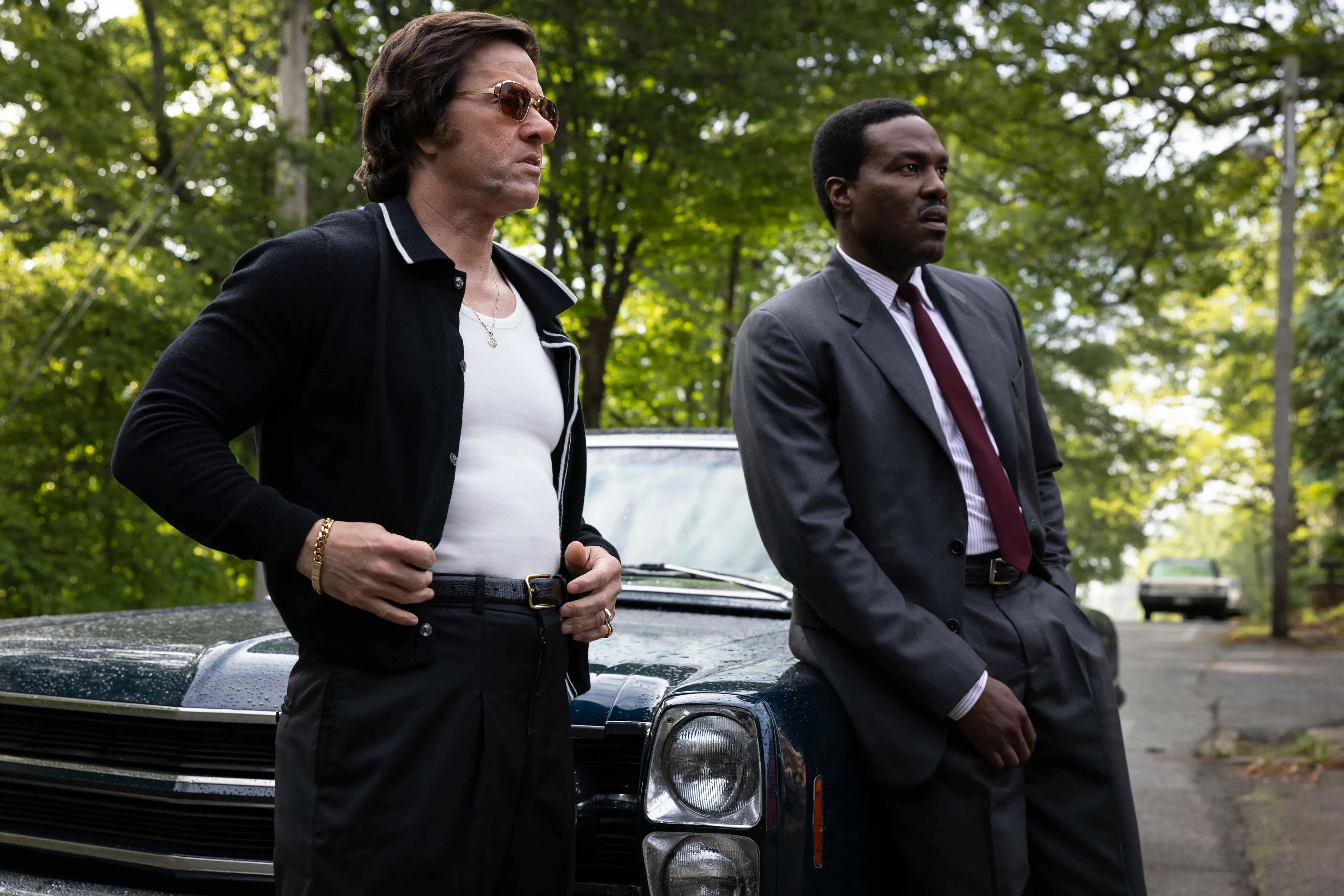 Two lead actors from the film "By Any Means" are pictured standing in the woods.
