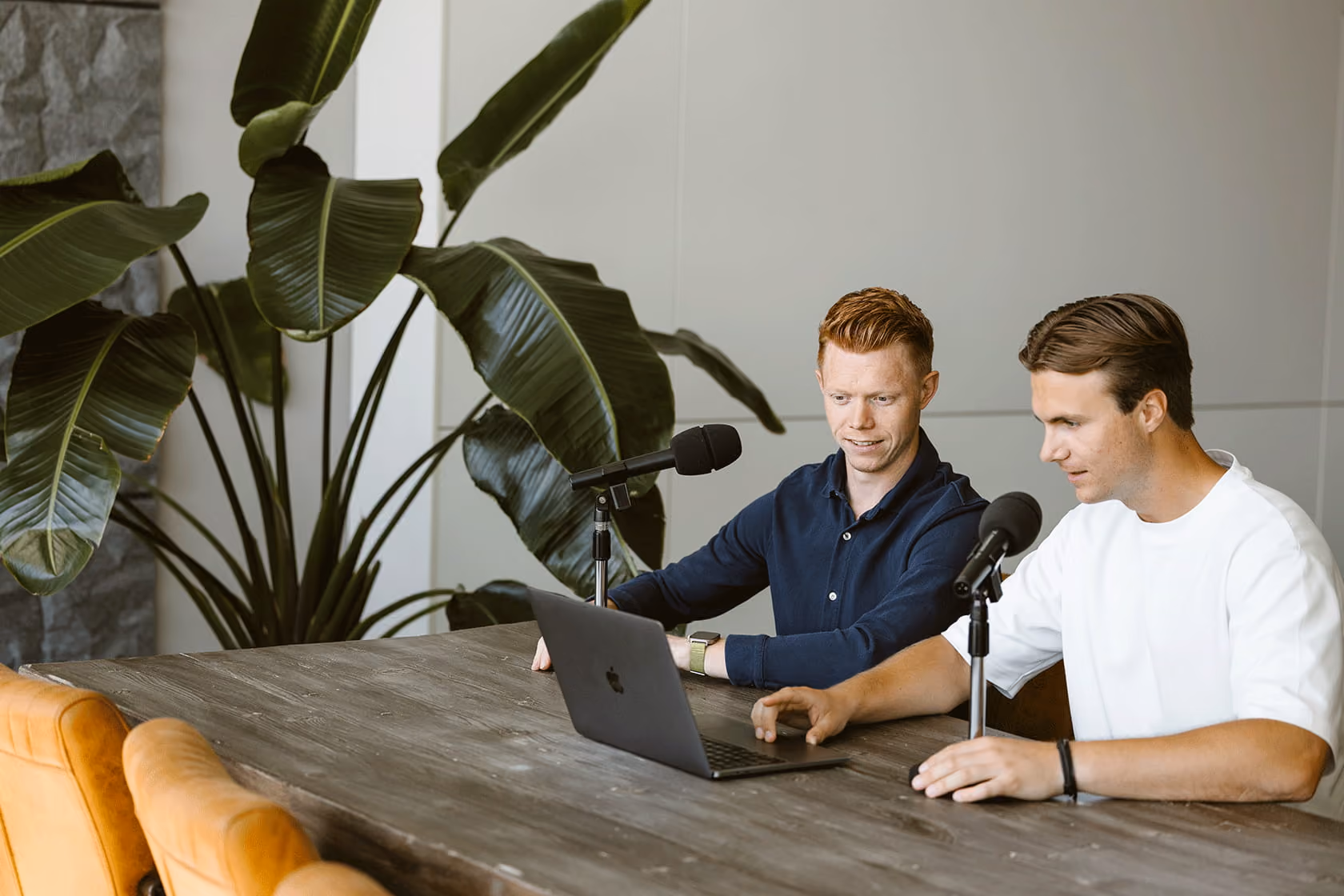 Mensen werken samen aan computers in een lichte kantoorruimte met meerdere schermen op een lange tafel.
