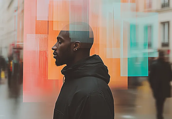 Profile of a man in a black jacket standing against a blurred urban background with colorful translucent panels.