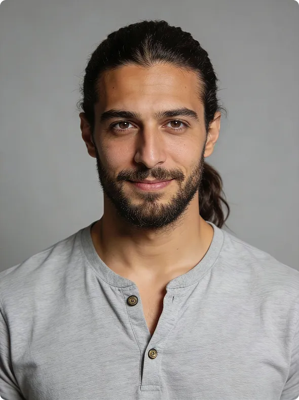 Smiling man with beard and long hair tied back wearing a light gray henley shirt against gray backdrop.