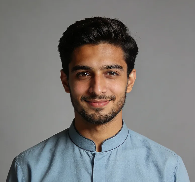 Smiling young man with dark hair and beard wearing a light blue shirt against a gray background.