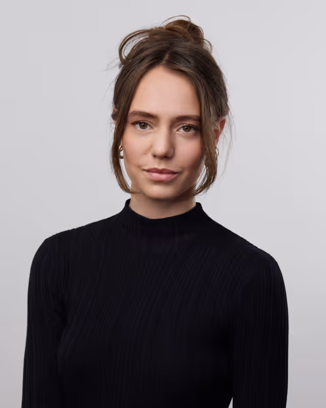 Portrait d'une femme aux cheveux bruns relevés portant un pull noir à col montant.