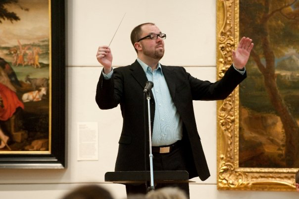 A conductor stands before an audience