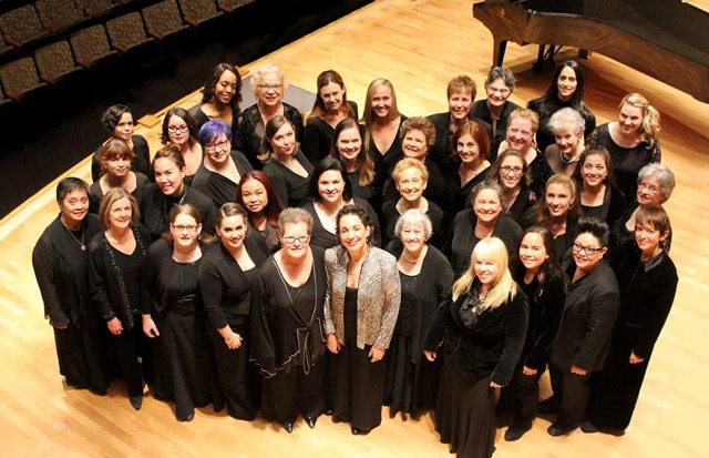 A group of people smile up at the camera while standing on a stage