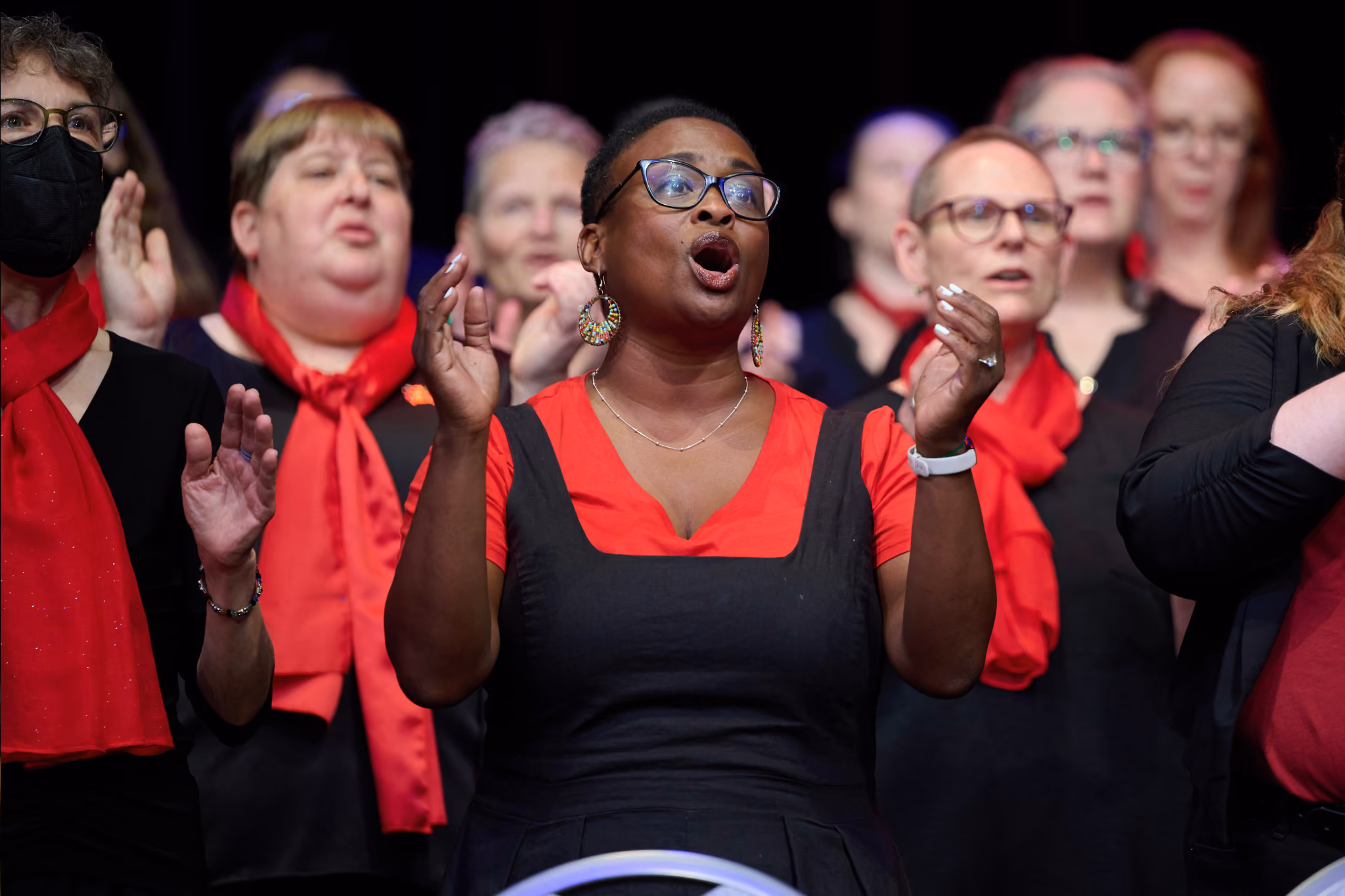 A woman sings expressively among fellow choristers as the Bayard Rustin Festival Chorus and OUTside VoicesKC perform at GALA Choruses Festival 2024