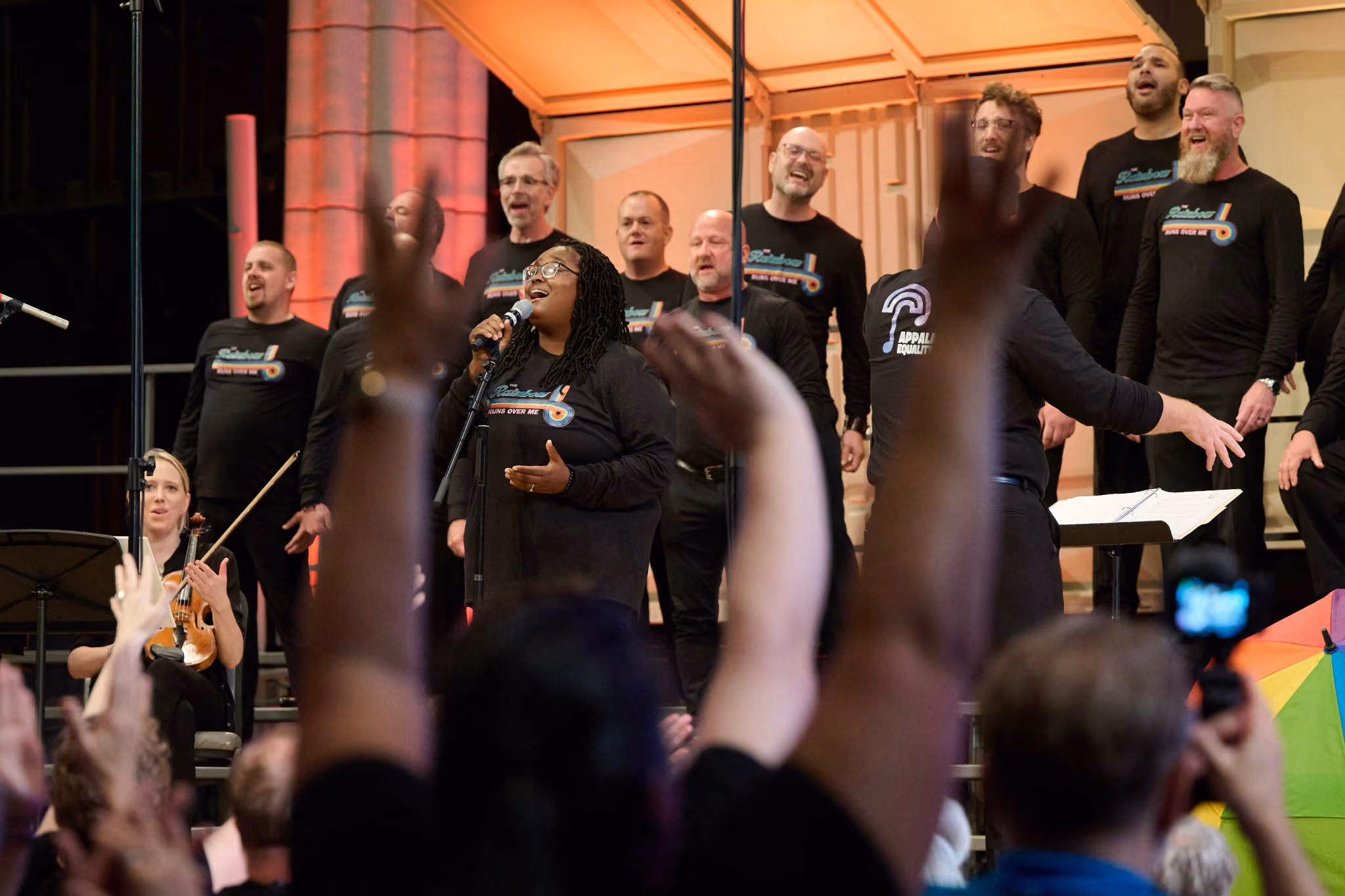 The Appalachian Equity Chorus performing at GALA Festival 2024 to an excited audience standing with their hands in the air.