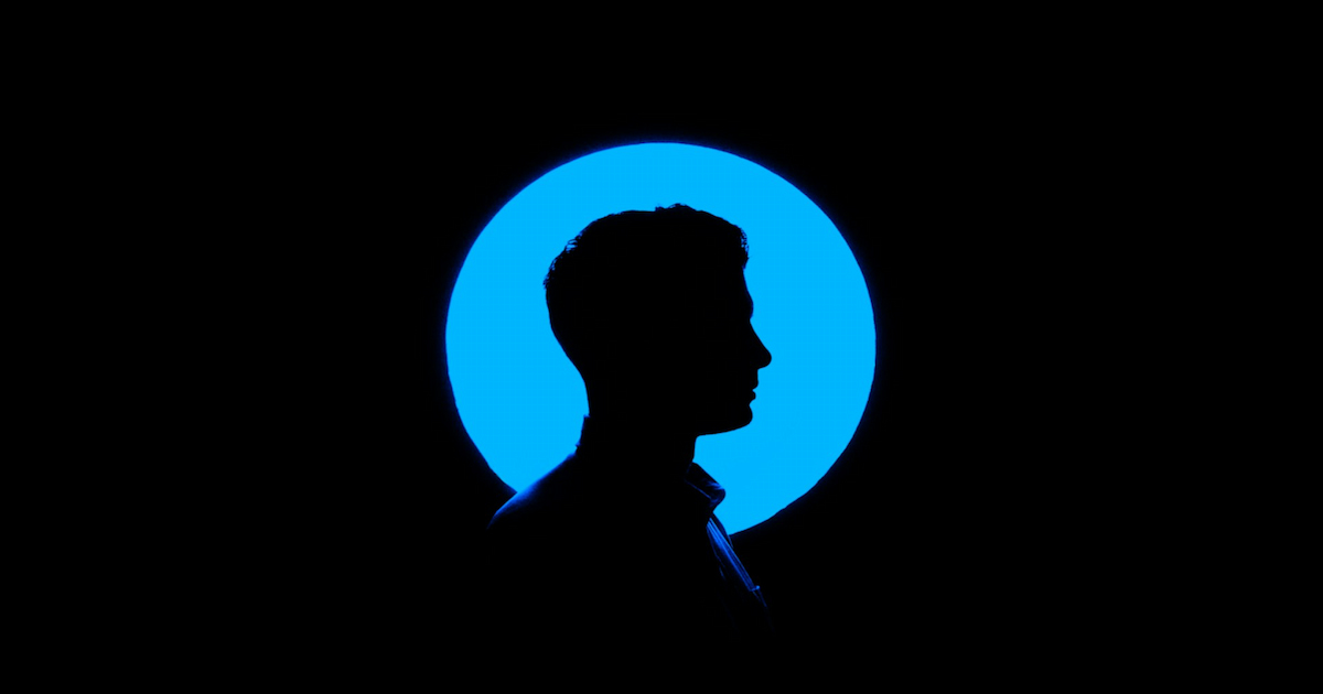 Silhouette of a person in front of an illuminated blue circle against a dark background