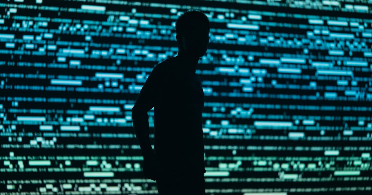 Silhouet van een persoon voor een groot scherm met blauwgroene datalijnen
