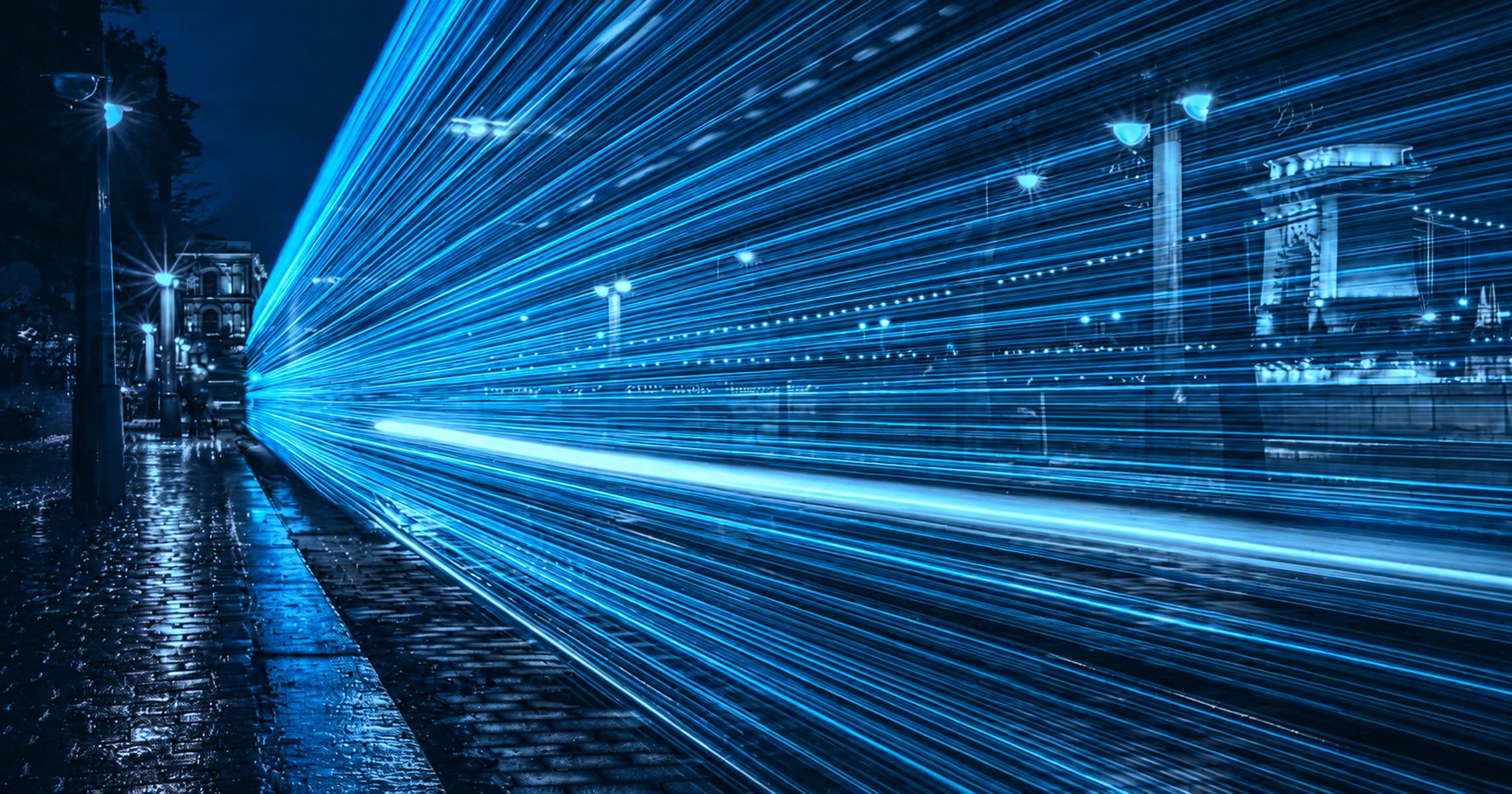 Blauwe lichtsporen in een stedelijke omgeving als beeld voor snelheid en automatisering in cybersecurity