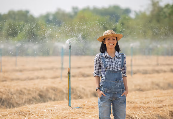 Agricultrice souriante dans un champ avec système d'arrosage automatique