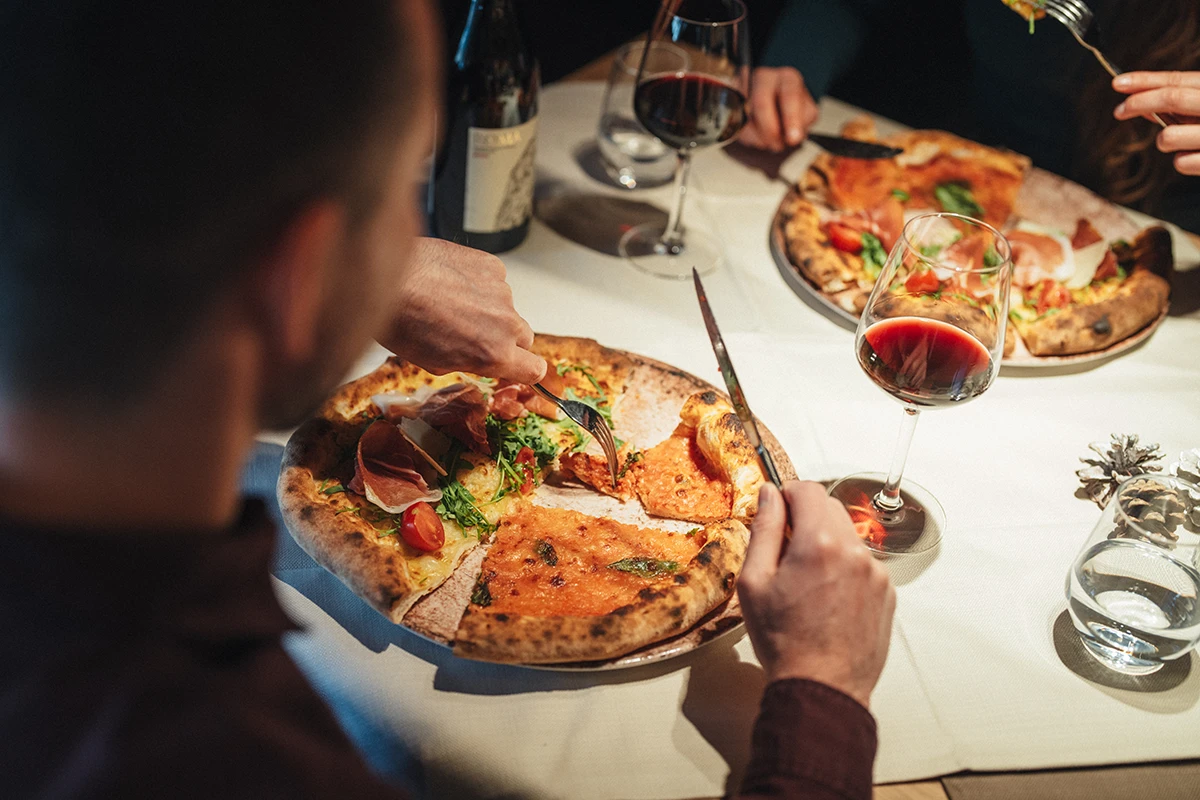 Guests share wood-fired pizzas and red wine at Da Vinci restaurant in Täsch