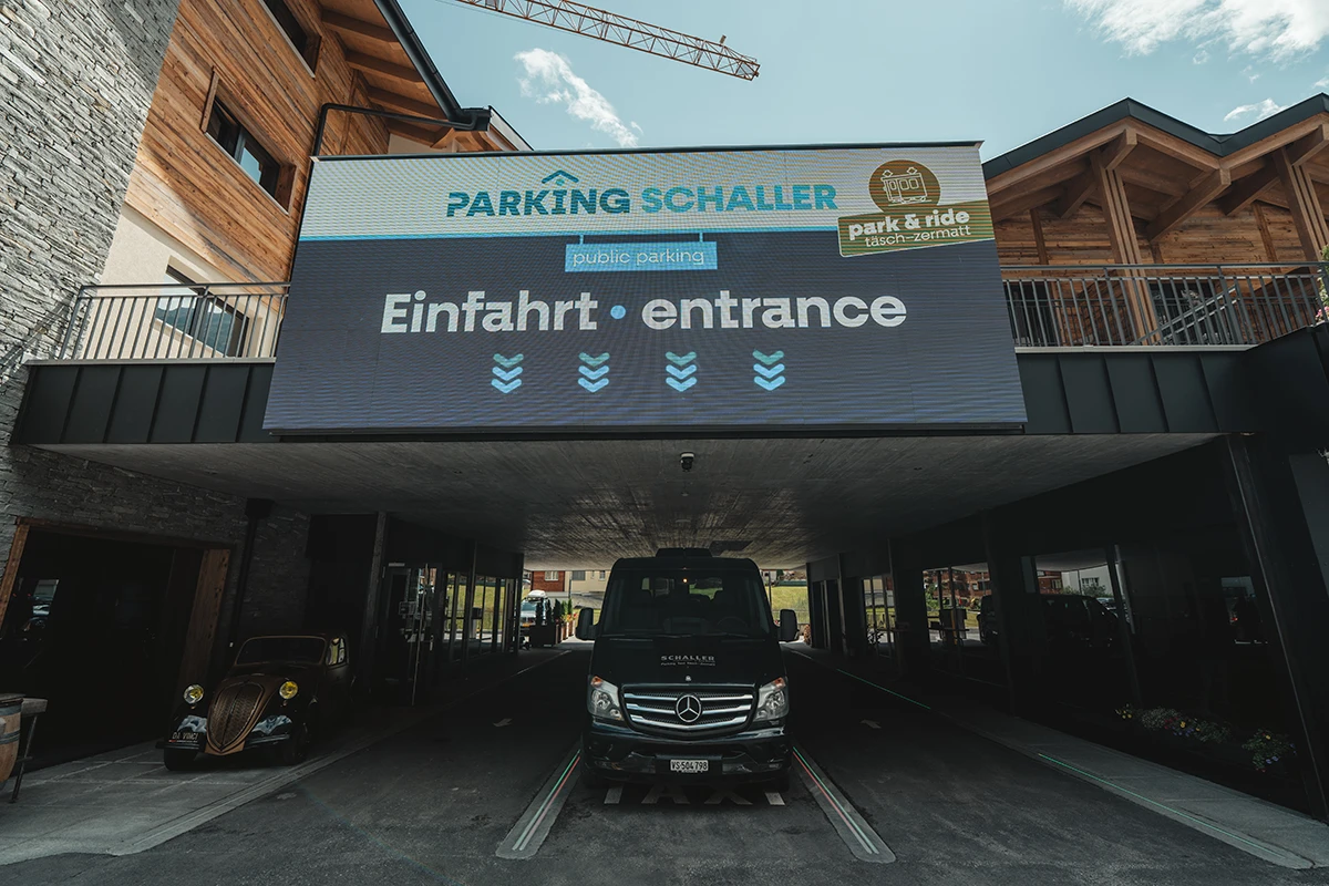 Entrance to the Schaller parking lot at the Hotel Porta Cervino in Täsch with a black shuttle van