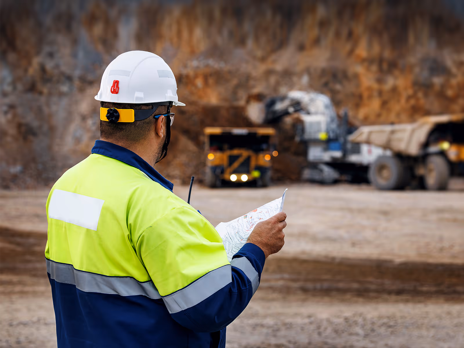 A miner working and overlooking the operation of the vehicles