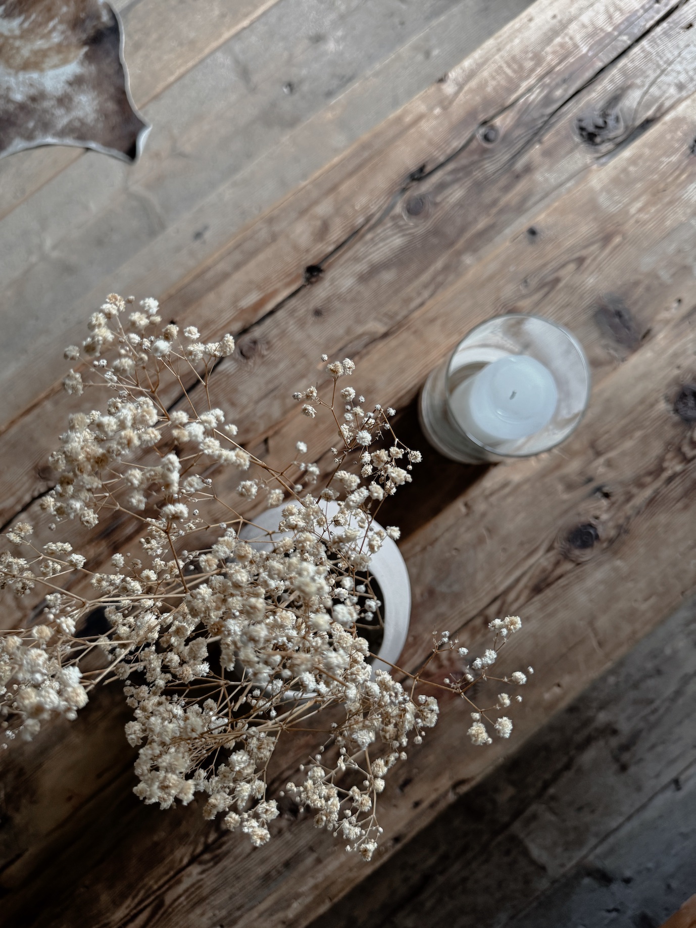 Trockenblumen und Kerze auf historischem Holztisch