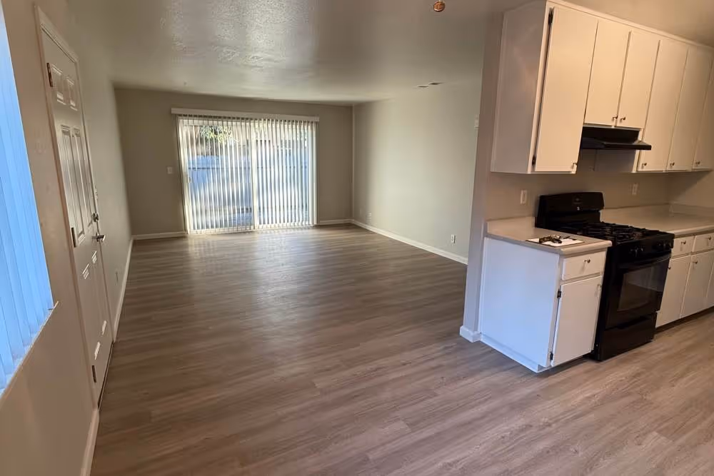 Kitchen with white cabinets and black appliances and view of unfurnished living area