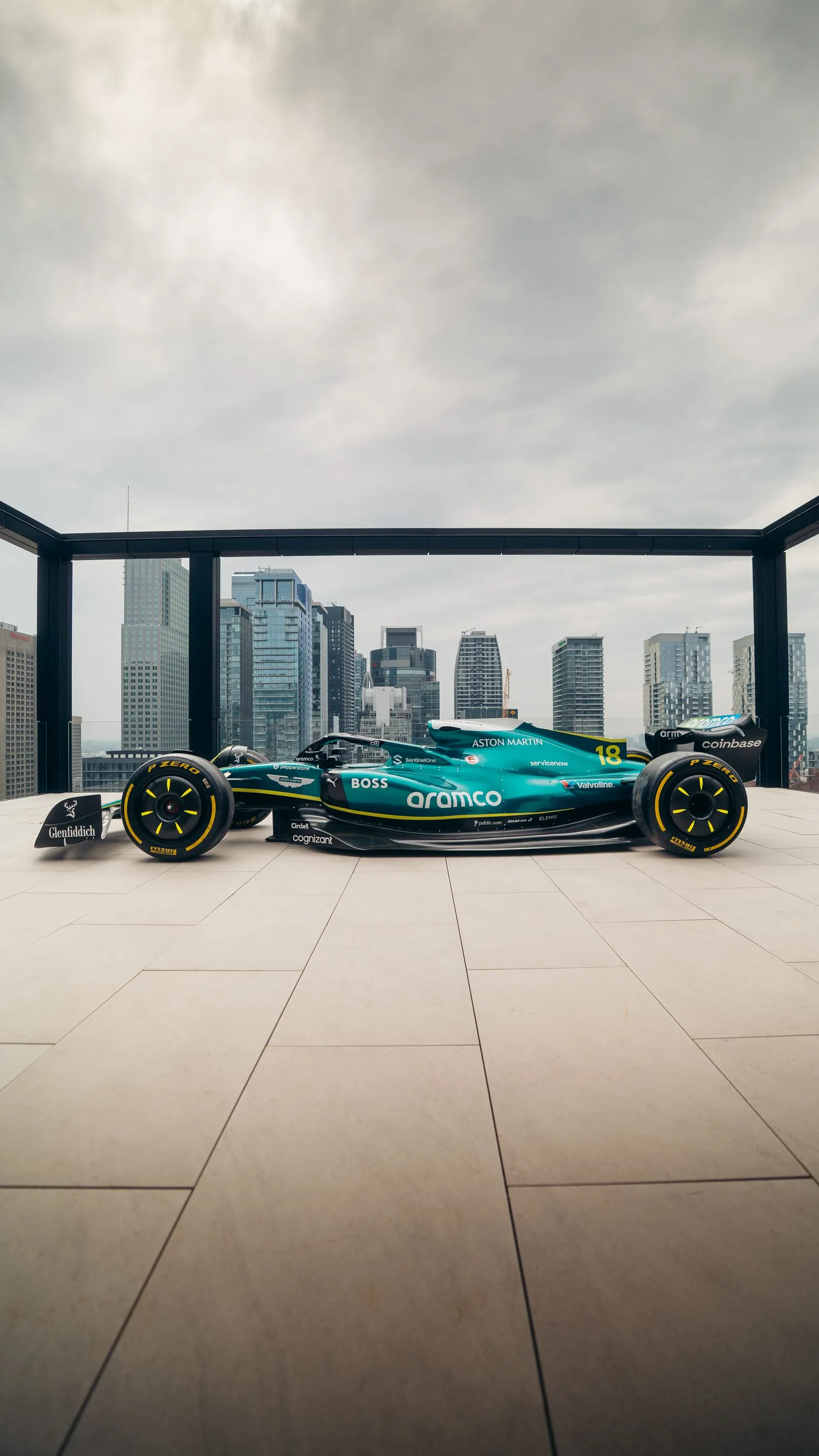 Green Aston Martin Formula 1 race car with number 18 displayed against a city skyline.