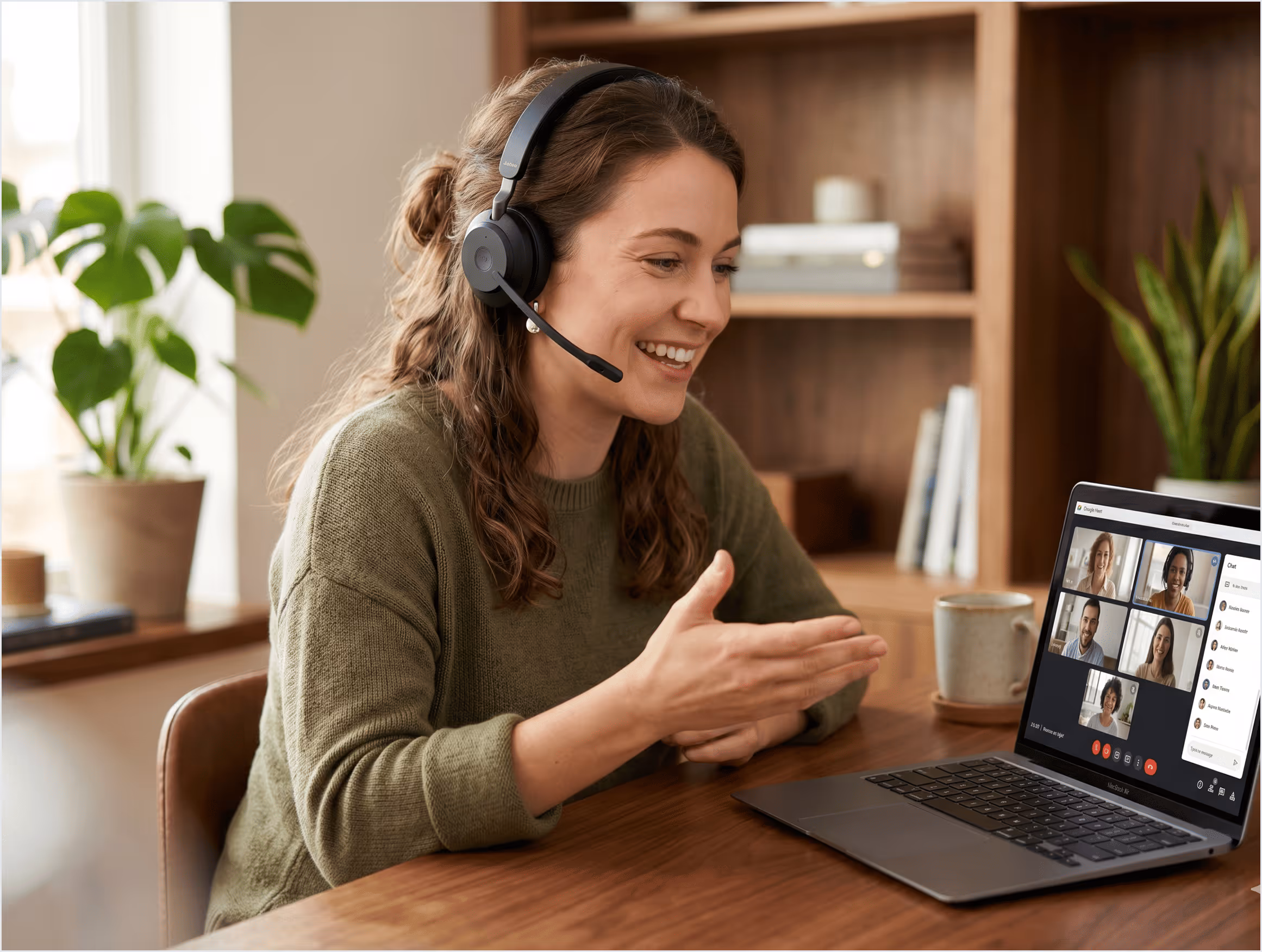 Femme souriante en visioconférence sur ordinateur portable avec casque à micro en intérieur.