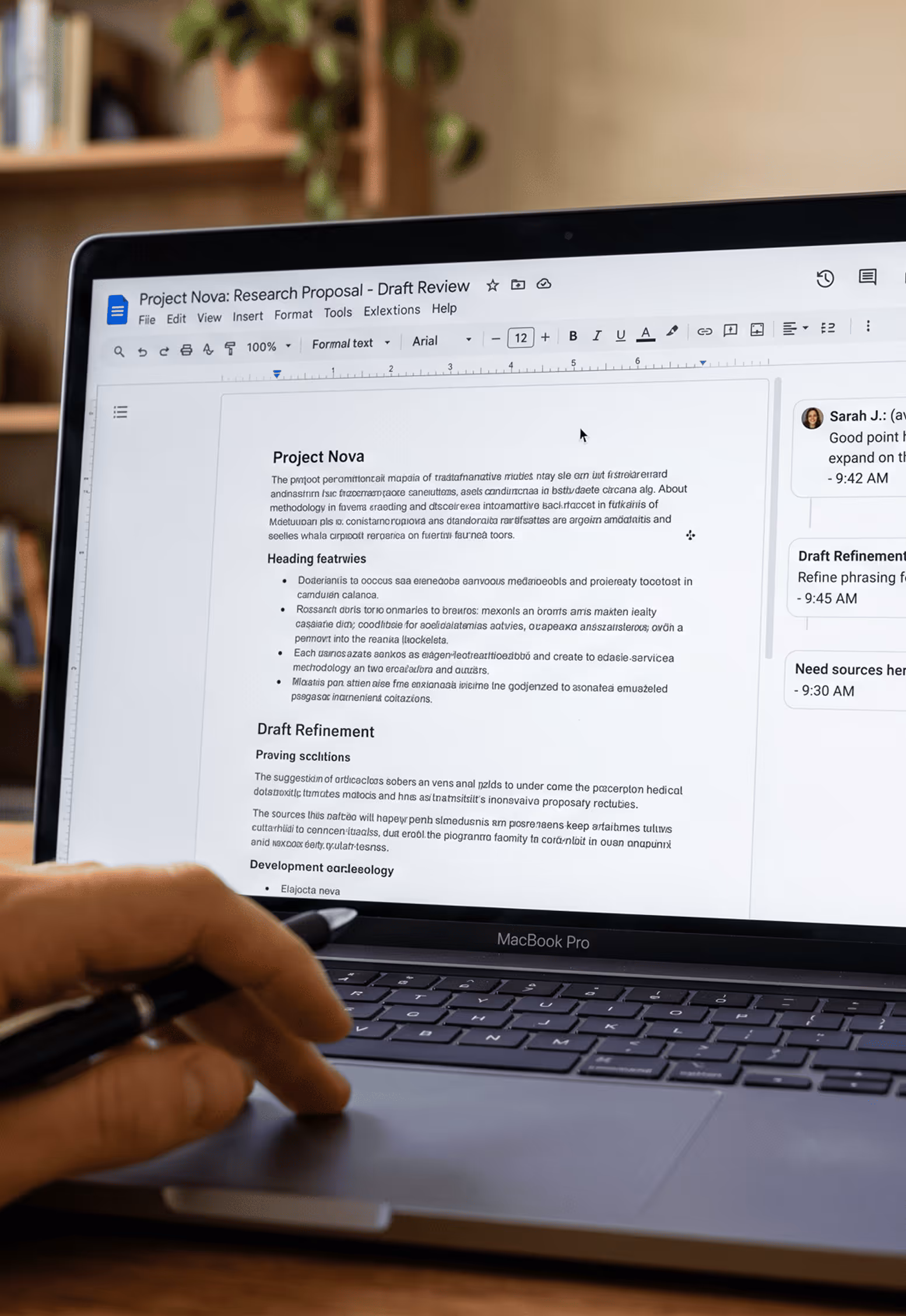 Main avec stylo sur clavier MacBook Pro montrant une proposition de recherche sur l'écran.