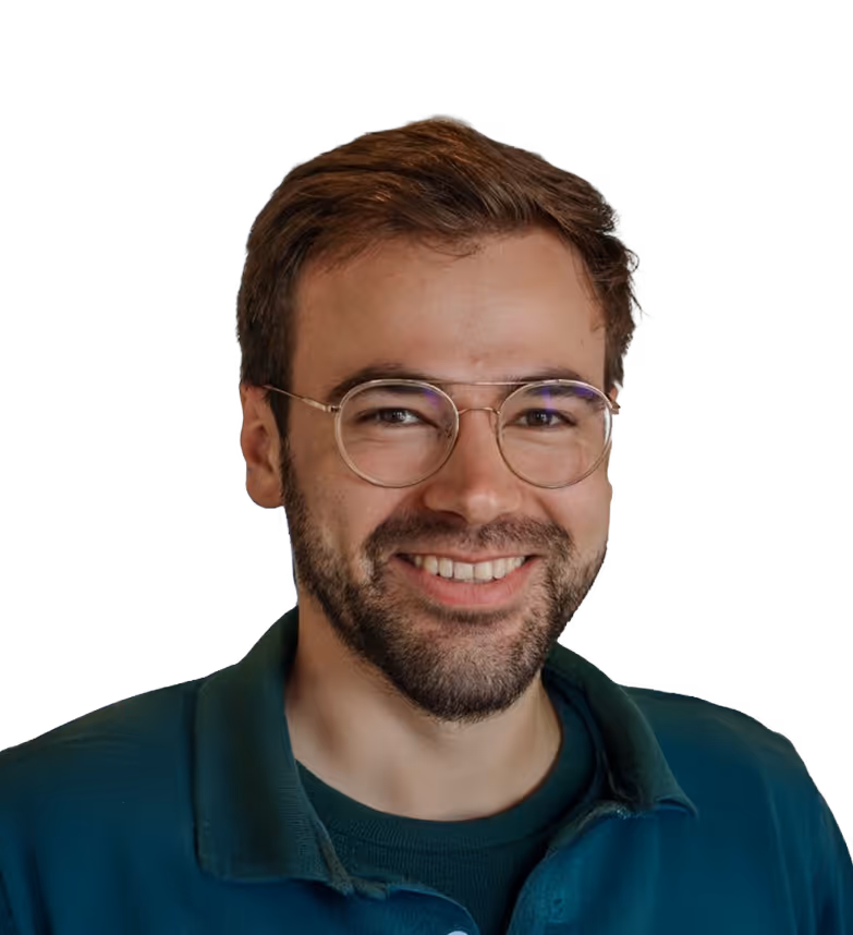 Homme souriant avec des lunettes rondes portant un polo vert foncé.