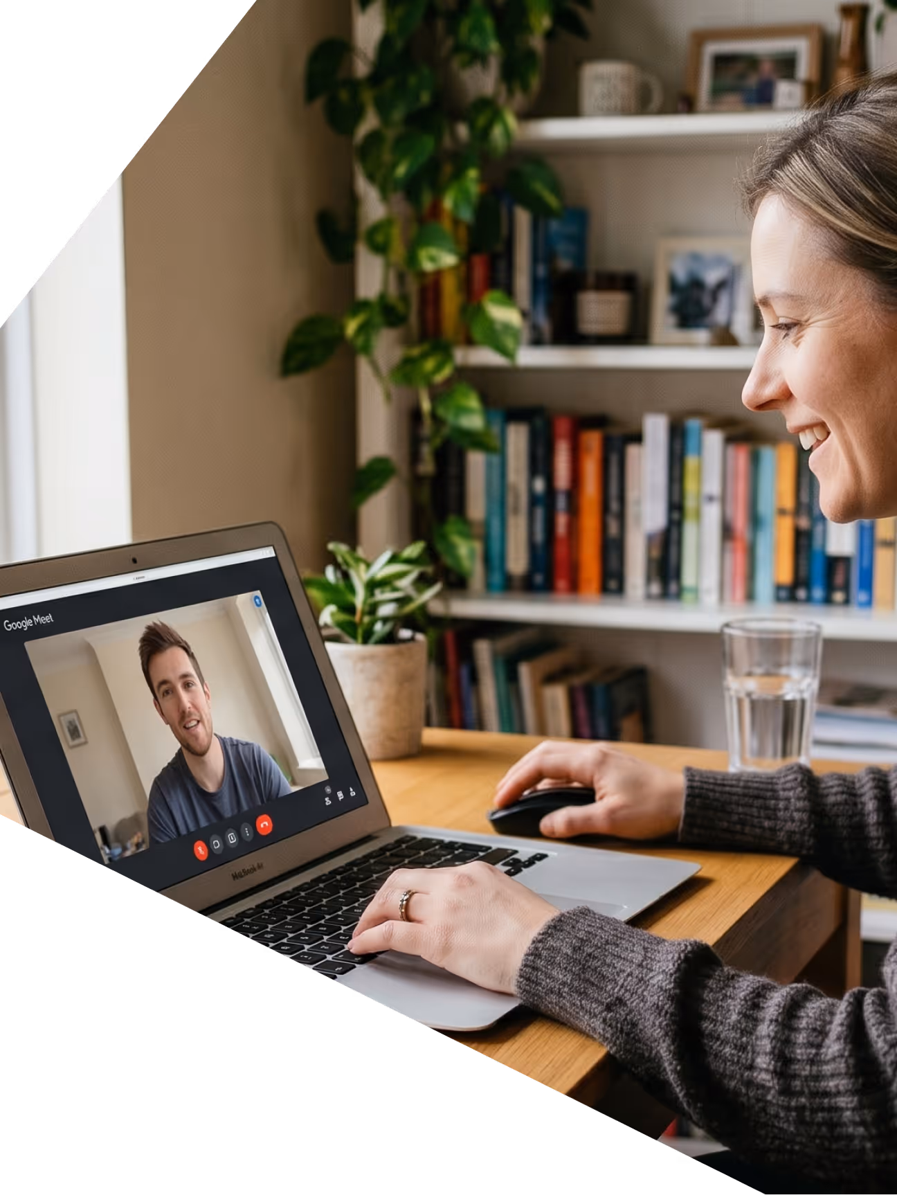 Une femme souriante utilisant un ordinateur portable pour un appel vidéo avec un homme sur Google Meet.