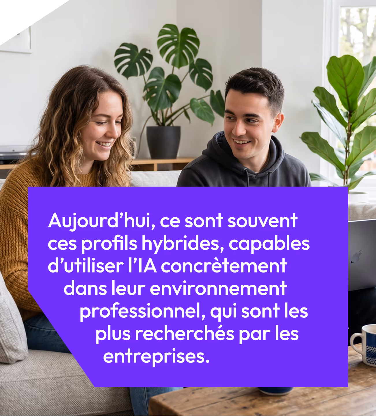 Deux jeunes souriants discutent dans un salon moderne avec des plantes vertes en arrière-plan.