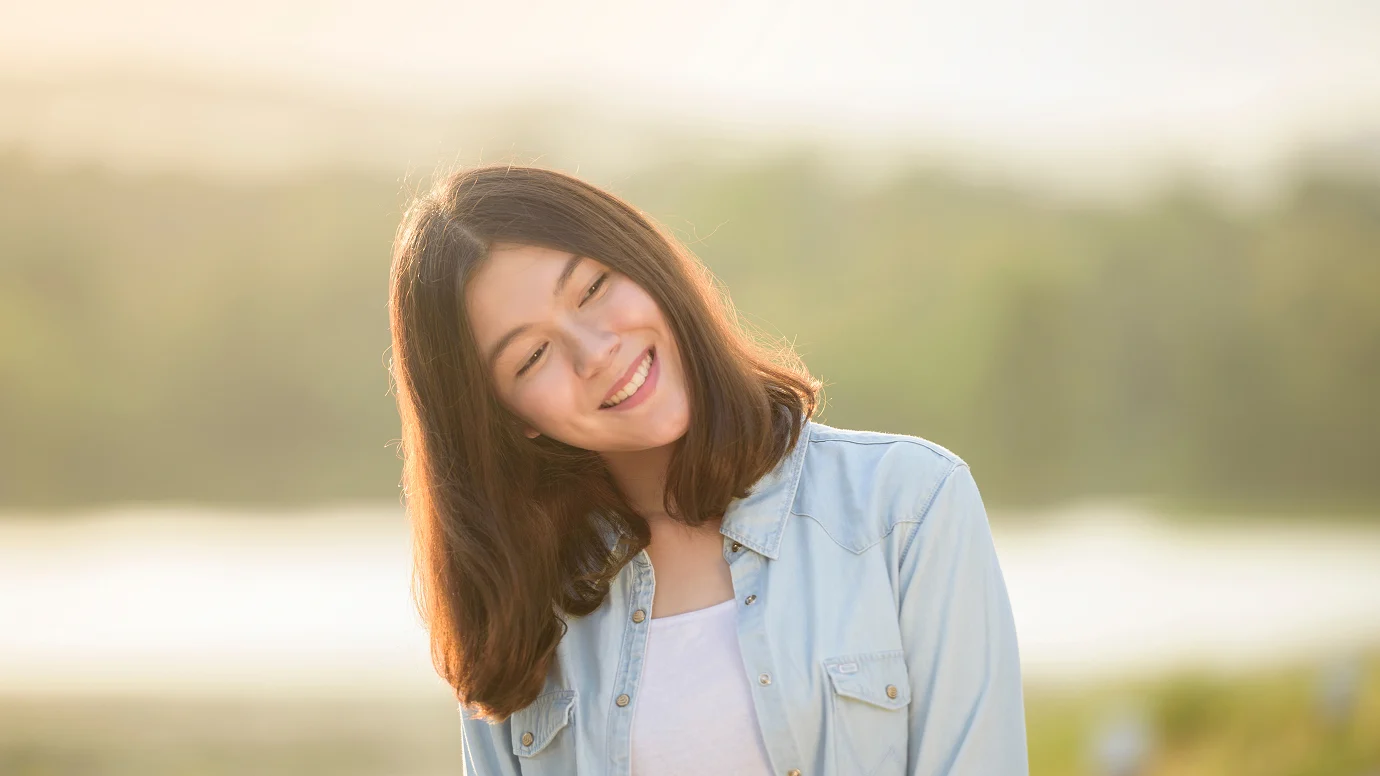 Donna con capelli castani folti sorride all'aperto dopo trapianto capelli