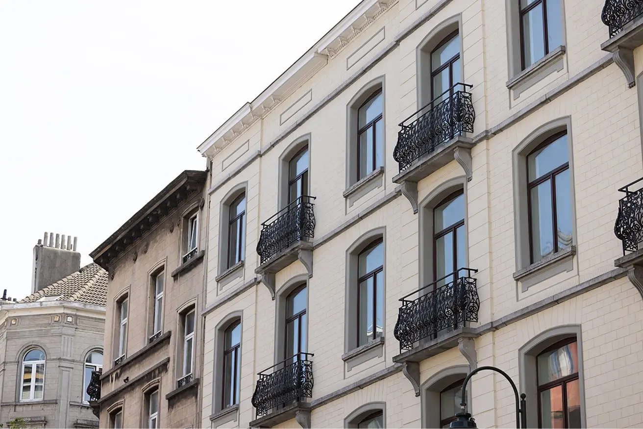 Facade of multi-story buildings with arched windows and decorative iron balconies on a clear day.