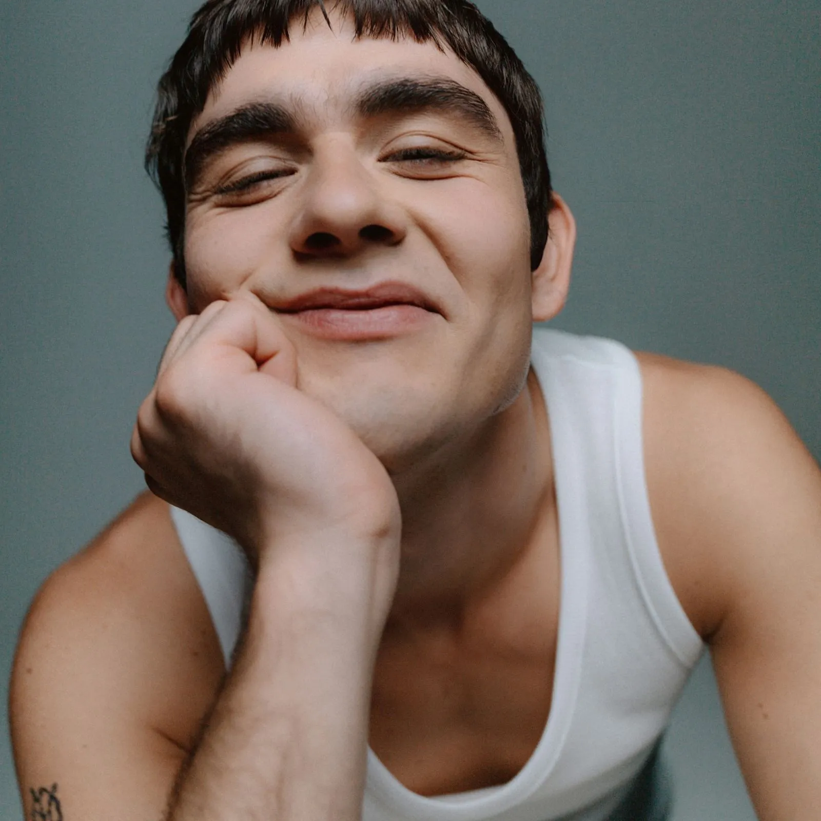 Mannequin masculin souriant, et la tête posée sur sa main