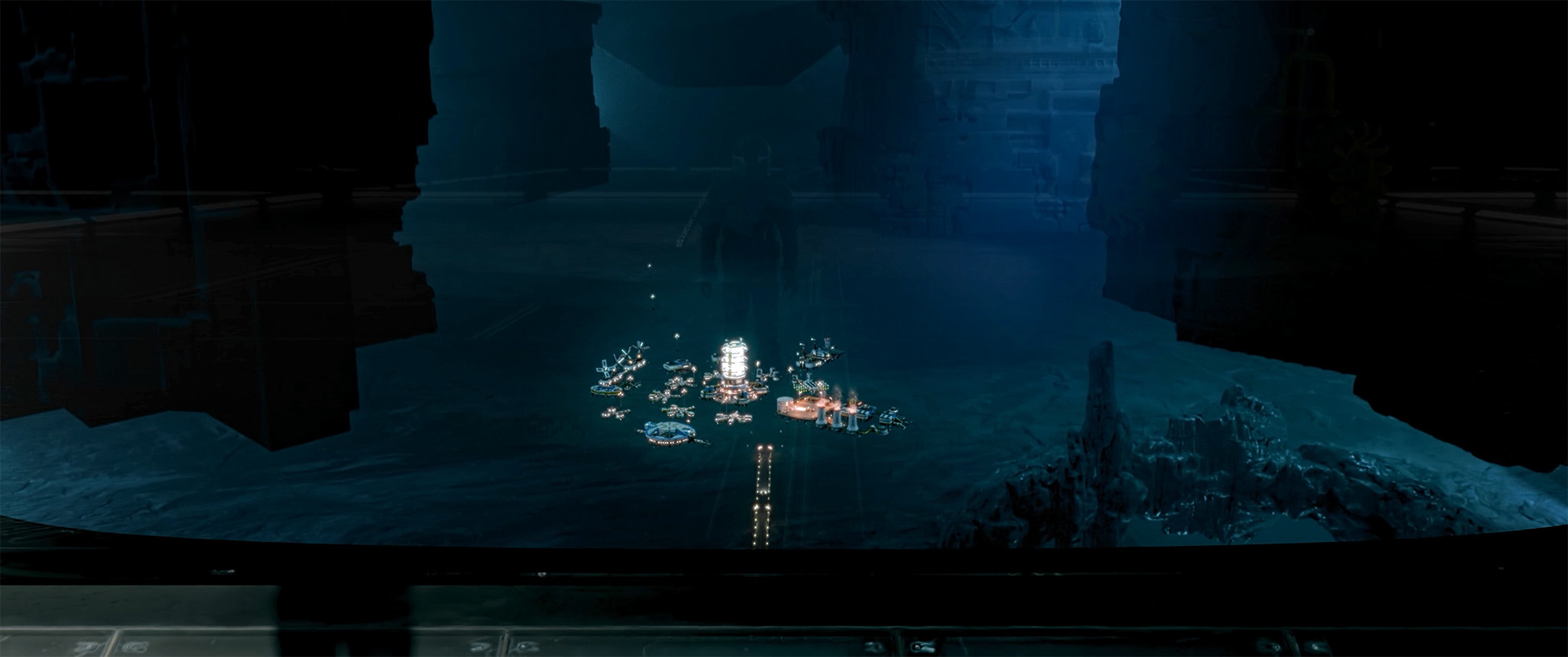 Futuristic illuminated space station model inside a dark cavernous structure, viewed from a window.