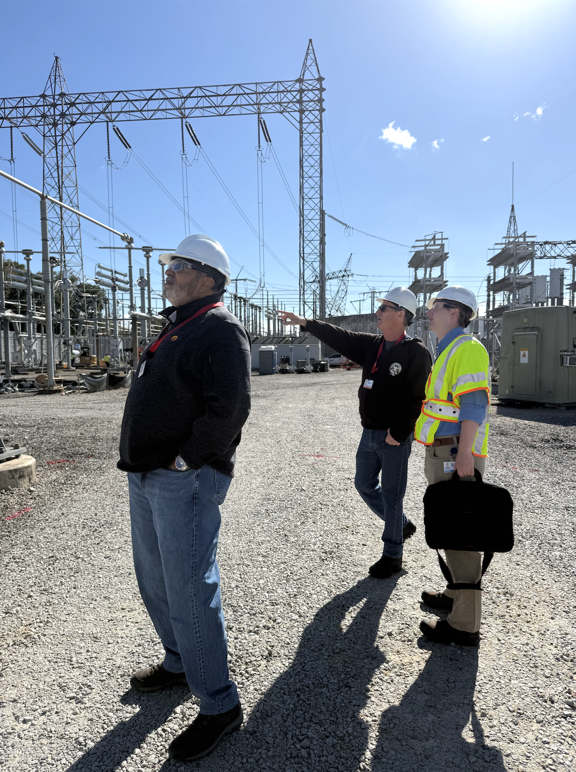Three Energy Grid Workers Seeing How Broadcast Positioning System Gets Installed at Power Station 